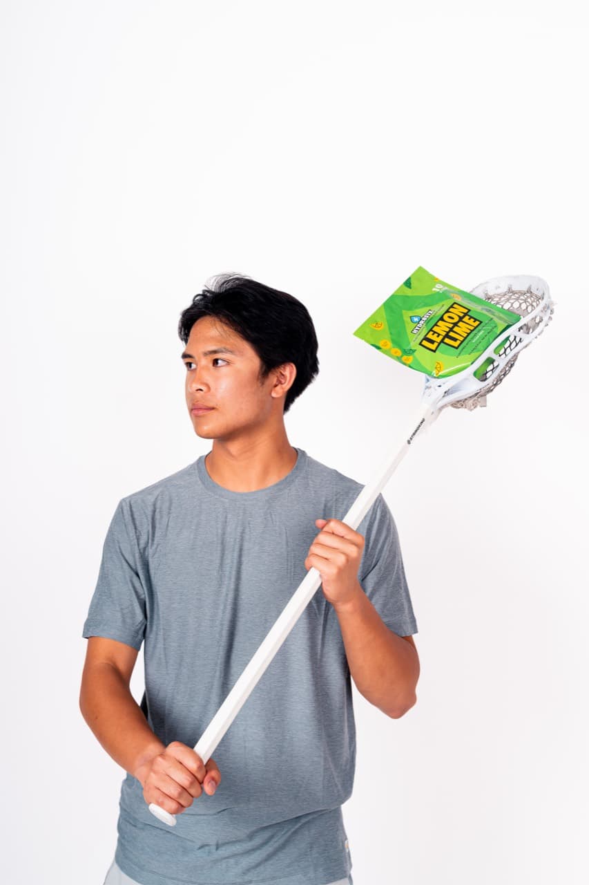Mason holding a lacrosse stick and Hydr8Stx Lemon Lime pouch